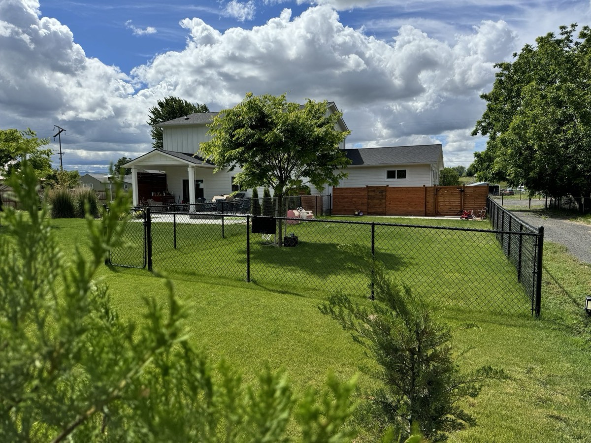 The white house with a large green lawn inside a black chain-link fence