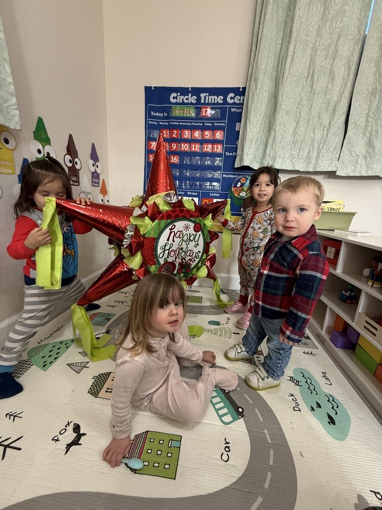 Four children in pajamas around a red star piñata on the play mat